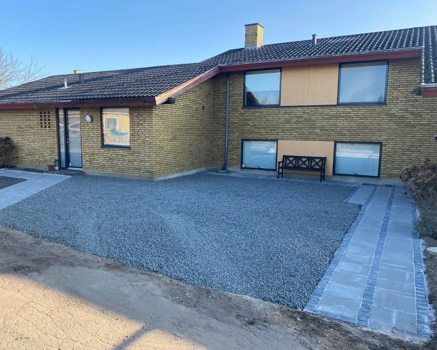 Grusindkørsel og flisesti ved et murstenshus
