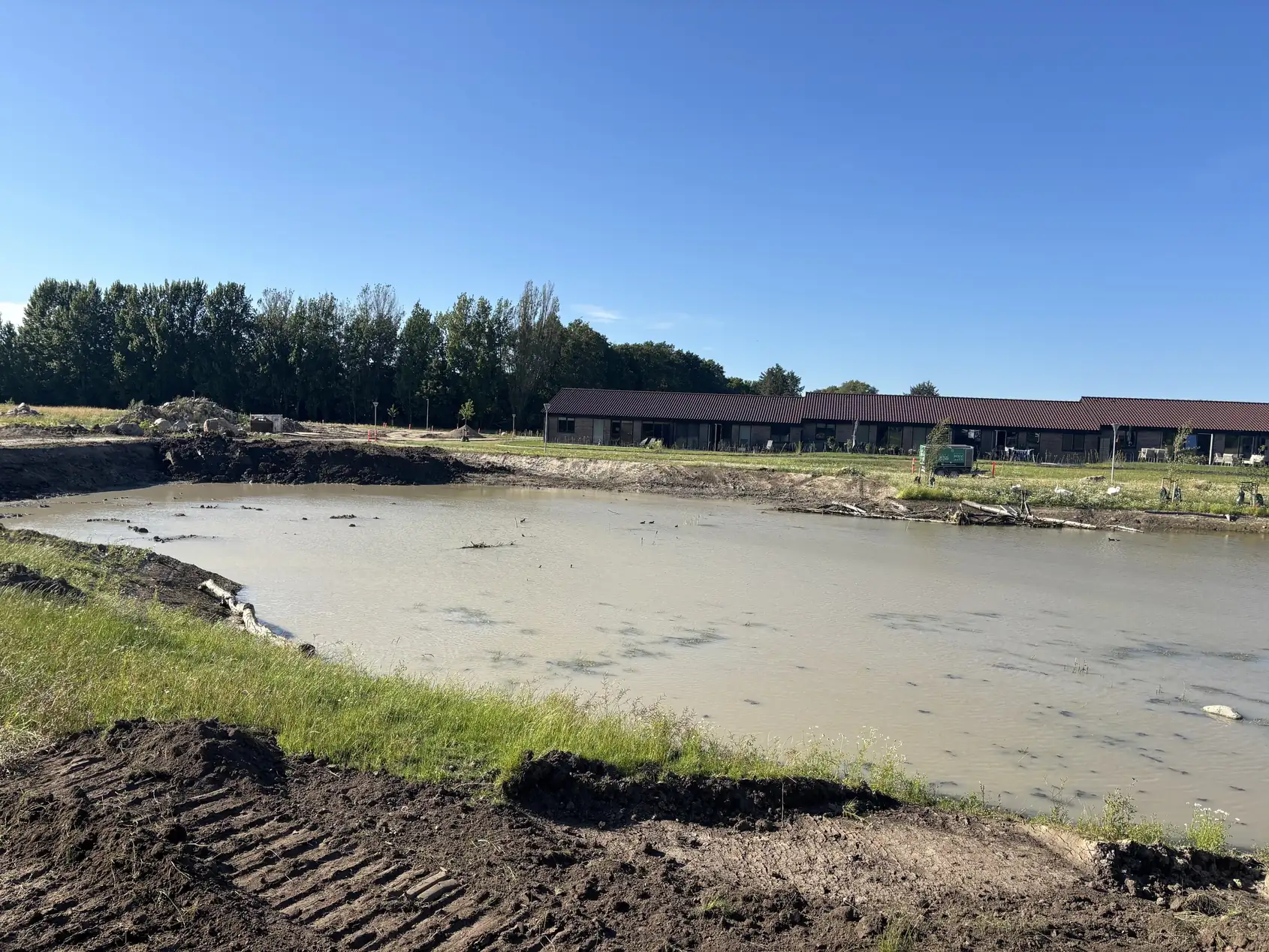 Udgravet bassin med vand og spor efter maskiner